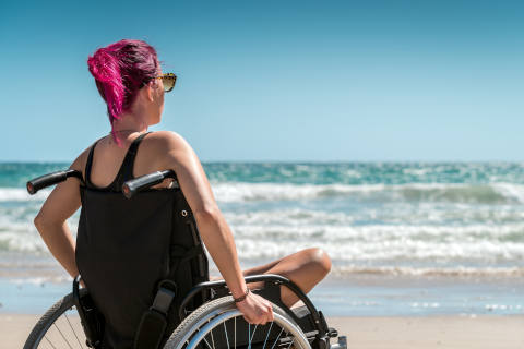 Disabled woman in wheelchair on beach