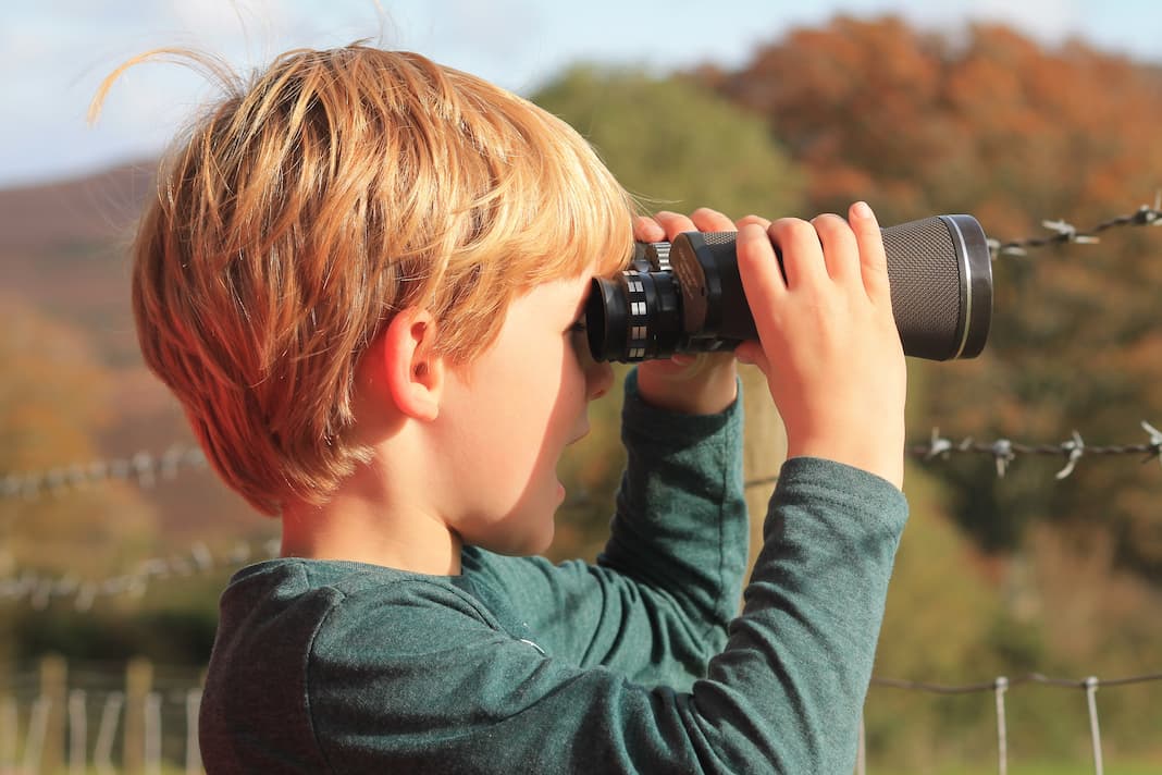 Blonde Caucasian boy exploring Exmoor through black binoculars